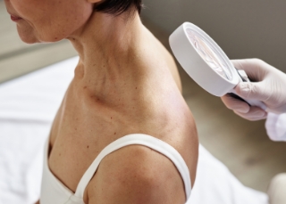 Dermatologist - Dermatologist examining back skin during check-up.